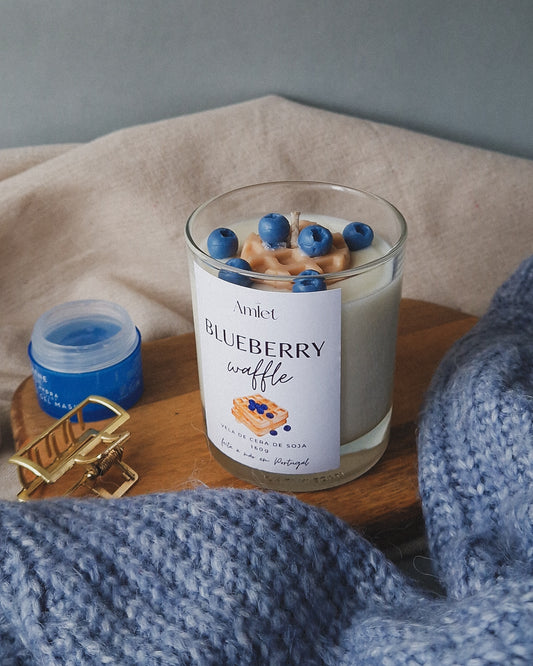 Vela em copo transparente com aroma de baunilha e mirtilos e com o topo da vela decorado com um waffle e vários mirtilos